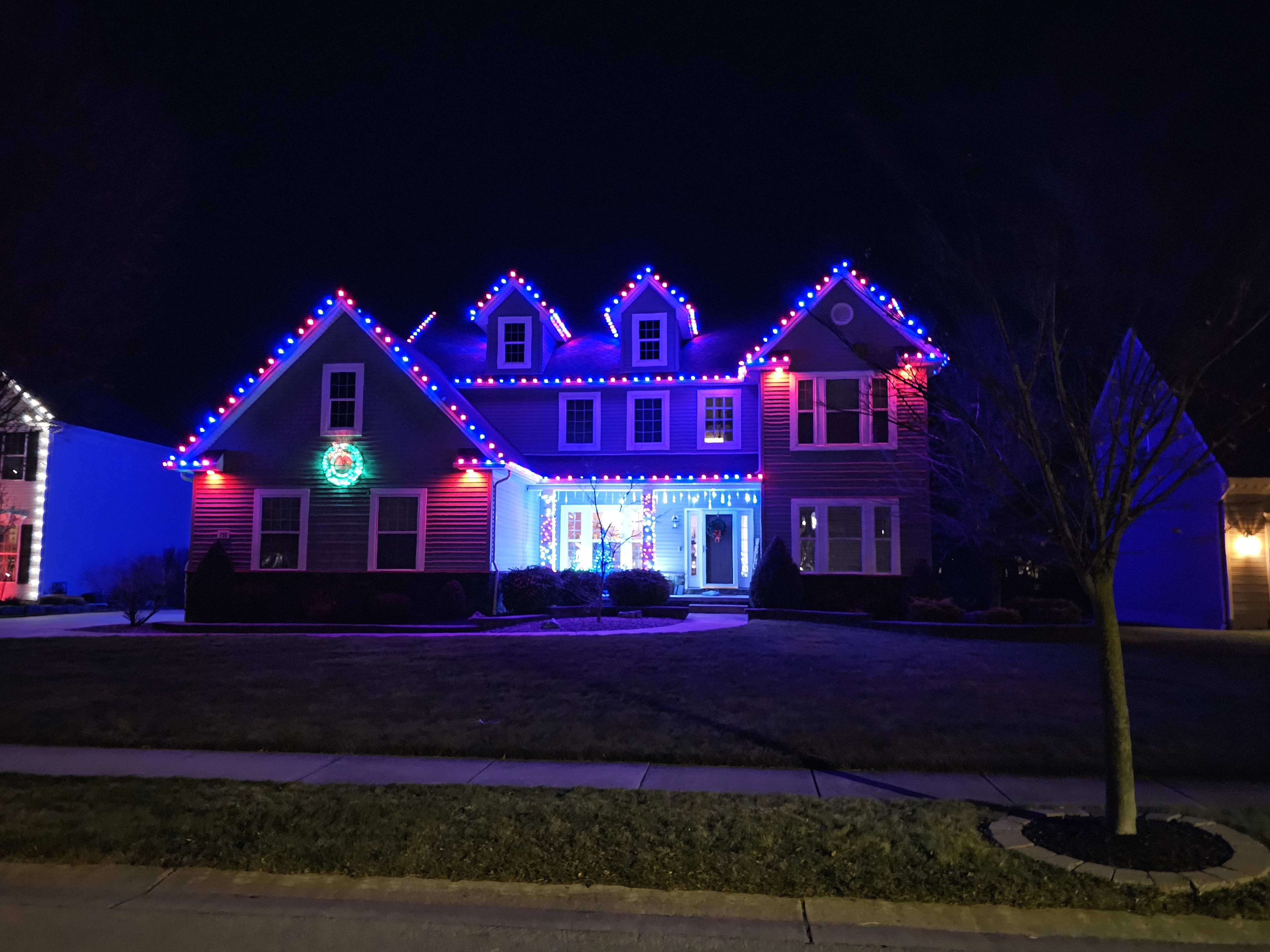 Red and blue holiday lighting on a snowy home by S&K Holiday Lighting