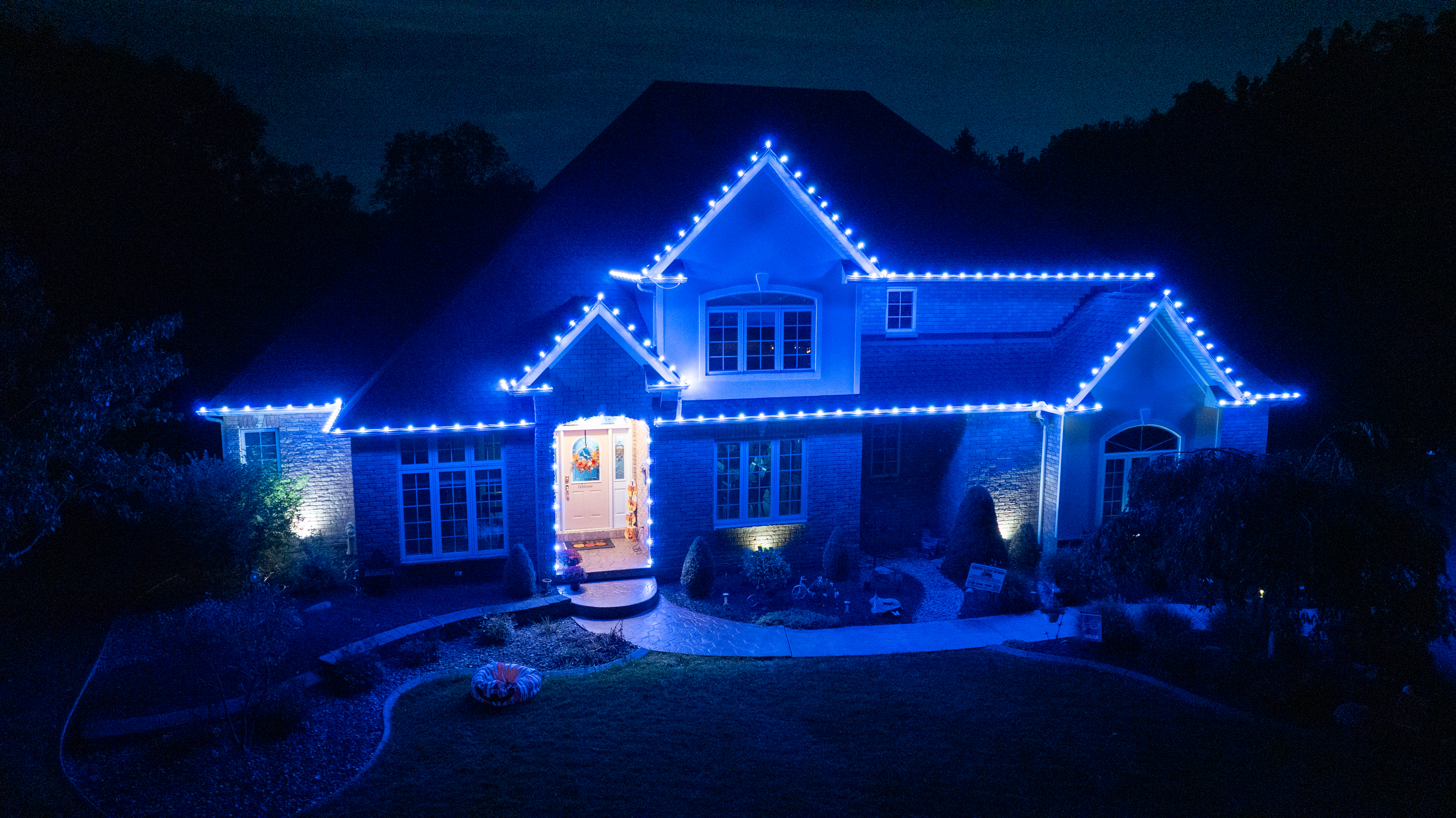 Home with bright blue and white holiday roofline lighting by S&K Holiday Lighting